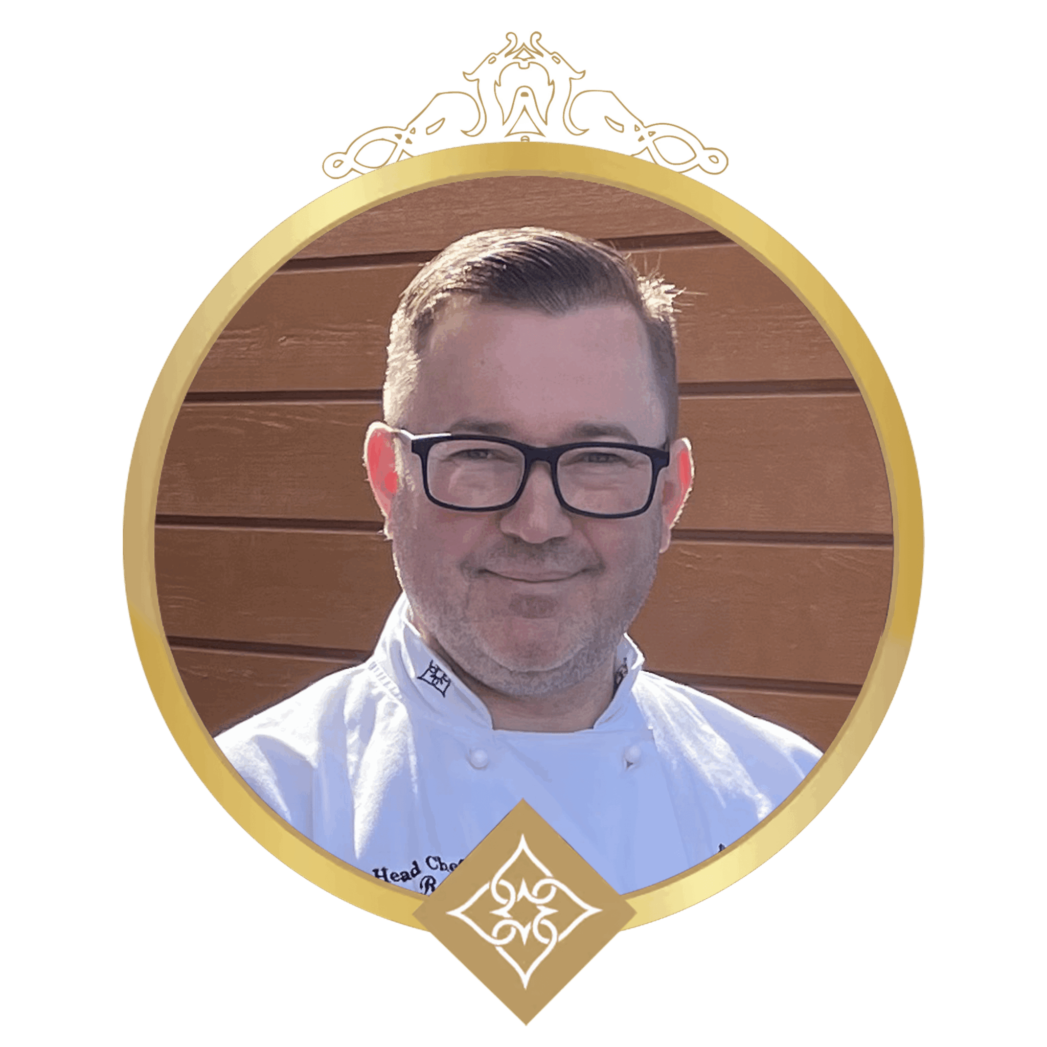 Portrait of a smiling man with dark hair and glasses wearing a white chef coat, posed in front of a wooden backdrop inside a gold circular medal frame with decorative crown embellishment at the top.